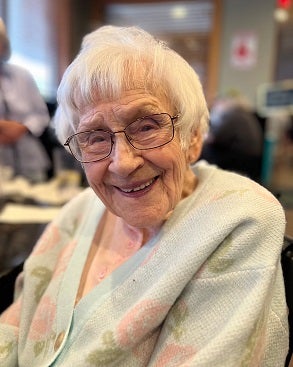 smiling woman with short white hair and glasses