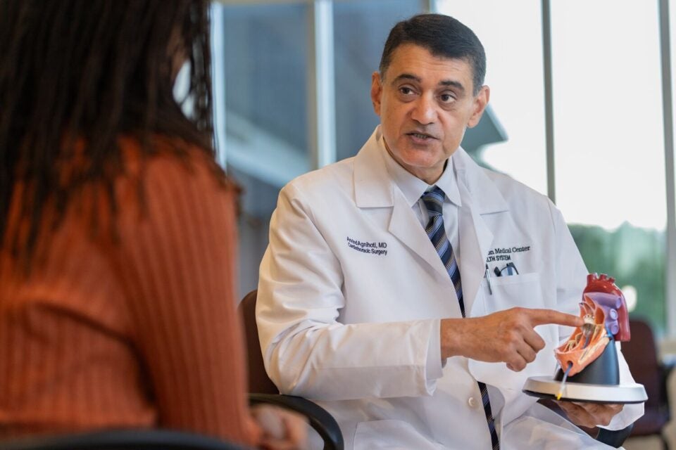 BMC Brighton cardiothoracic surgeon Arvind Agnihotri, MD, points to a model heart as he explains a procedure to a patient (face not shown)