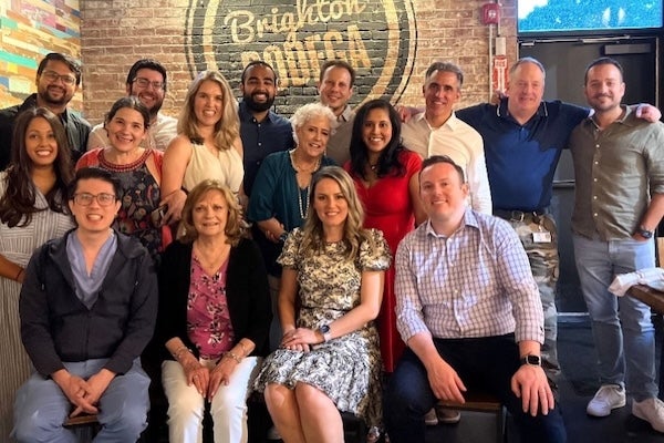 A group photo of pulmonary and critical care medicine fellows and faculty, indoors at a restaurant