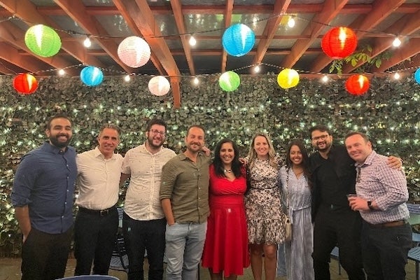 Group photo of BMC Brighton pulmonary and critical care medicine fellows at a holiday party (festive room with brightly colored lanterns)