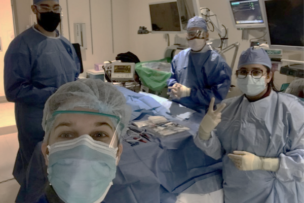 A candid shot of pulmonary and critical care medicine fellows in full scrubs and masks preparing for a procedure in the OR