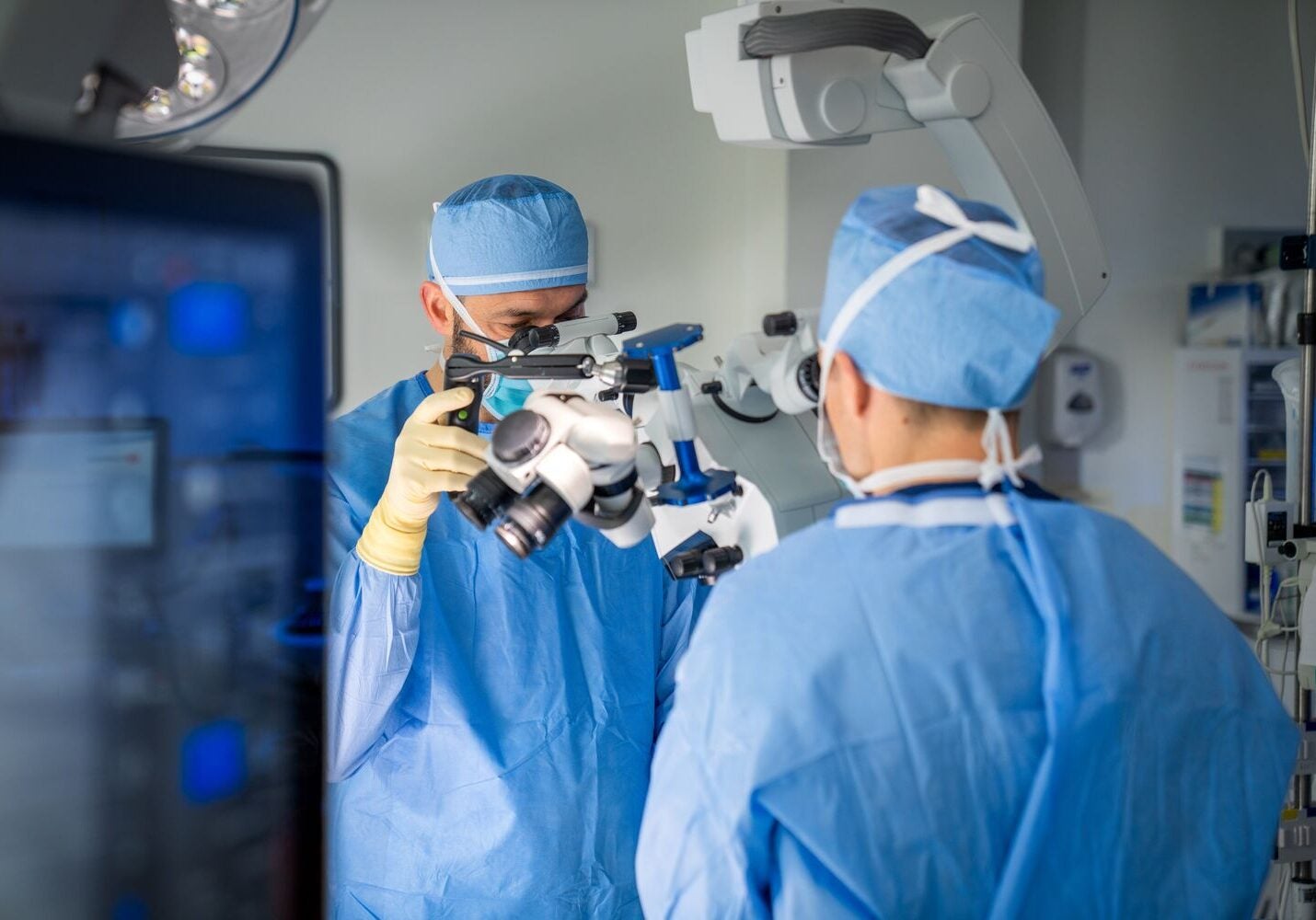 BMC Brighton neurosurgeons Serdar Kaya, MD, and Zachary Tataryn, MD, in surgical scrubs/caps/masks, examine a piece of equipment in the operating theater